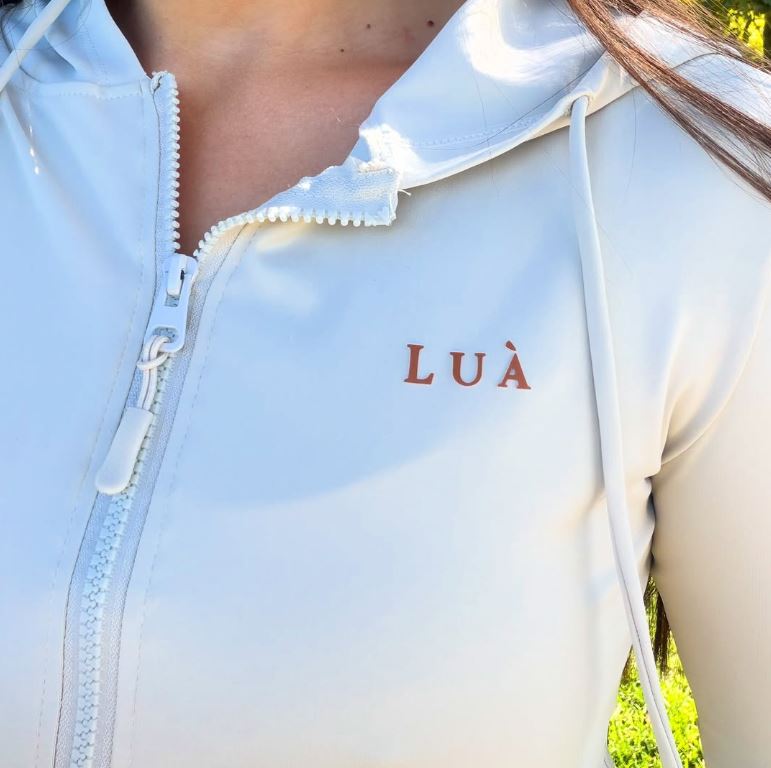 Detalhe da jaqueta creme LUÀ com o logo bordado em terracota