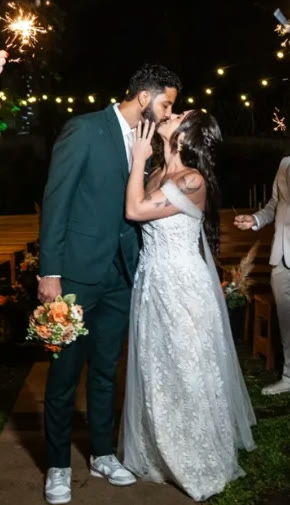 Thaina e o marido se beijando no casamento, sob luzes e faíscas