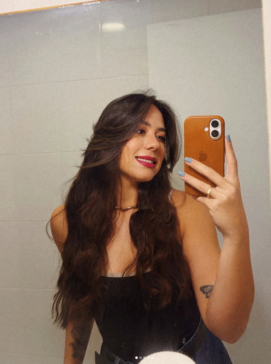 Thaina sorrindo em uma selfie no espelho